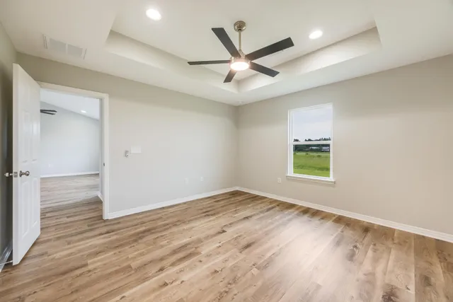 an empty room with wooden floor and ceiling fan