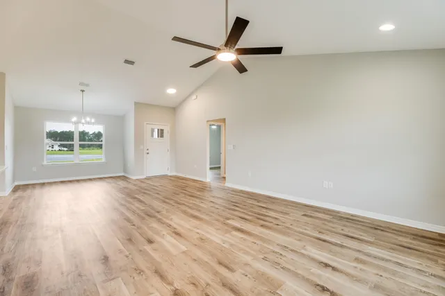 an empty room with wooden floor ceiling fan and windows