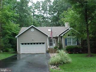10 Moonraker Road Ocean Pines, MD 21811 - Photo 1 of 6 a view of a white house next to a yard with plants and large trees