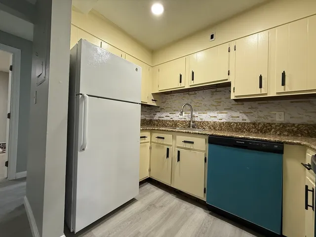 a kitchen with stainless steel appliances granite countertop a refrigerator a sink and white cabinets