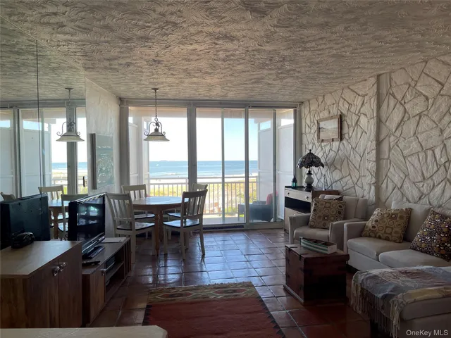 a living room with furniture large wooden floor and floor to ceiling window