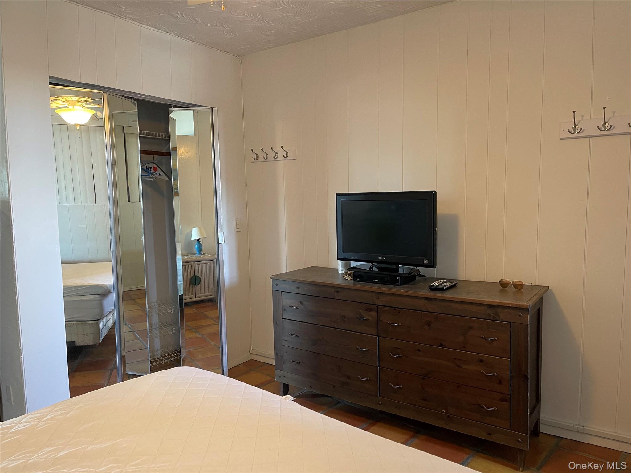 830 Shore Road, Unit 3E Long Beach, NY 11561 - Photo 9 of 13 a bedroom with a bed and a flat screen tv on dresser