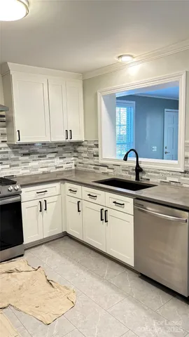 a kitchen with granite countertop white cabinets white appliances with a sink and dishwasher