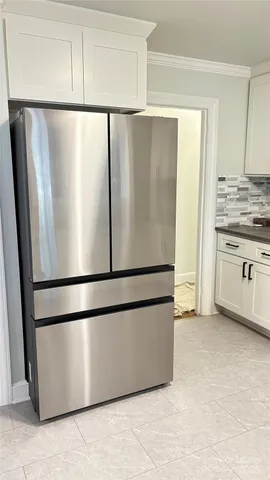 a view of a refrigerator in kitchen and white cabinets