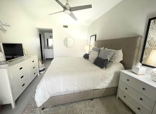 a bedroom with a bed and flat tv screen on the dresser