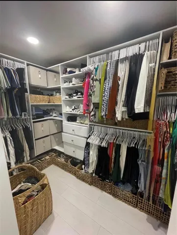 a view of walk in closet with clothes and shoes