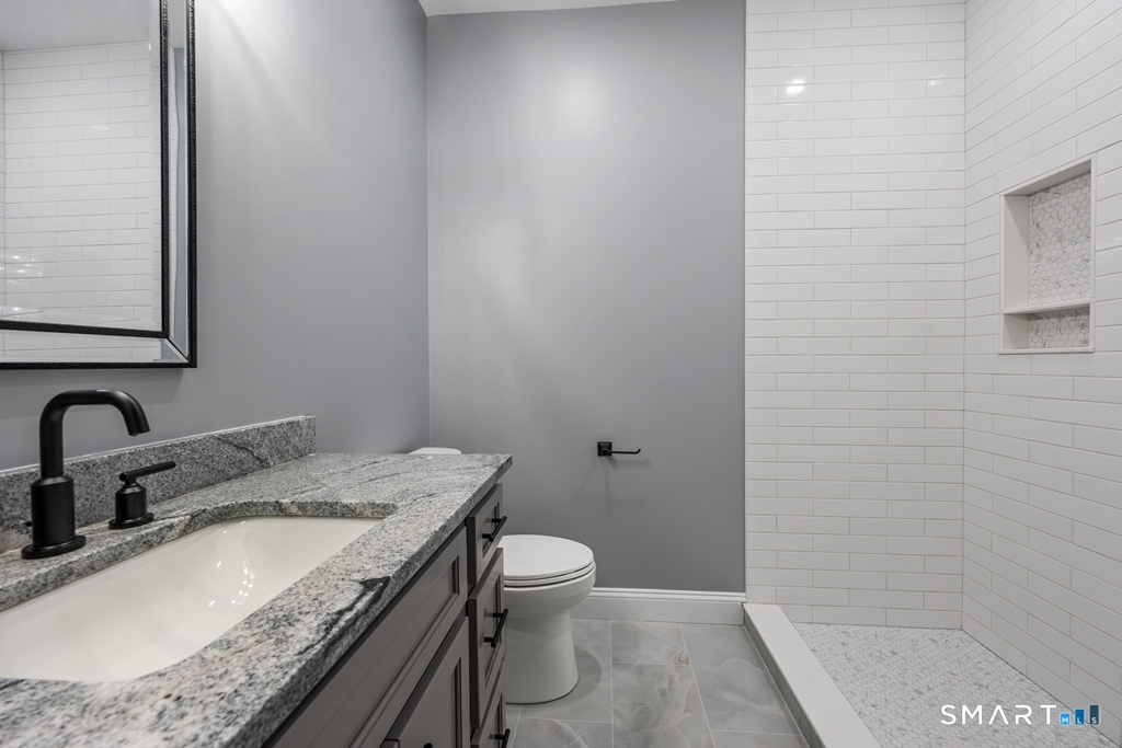 210 Munson Road, Unit 2G Wolcott, CT 06716 - Photo 19 of 23 a bathroom with a granite countertop sink a toilet and shower