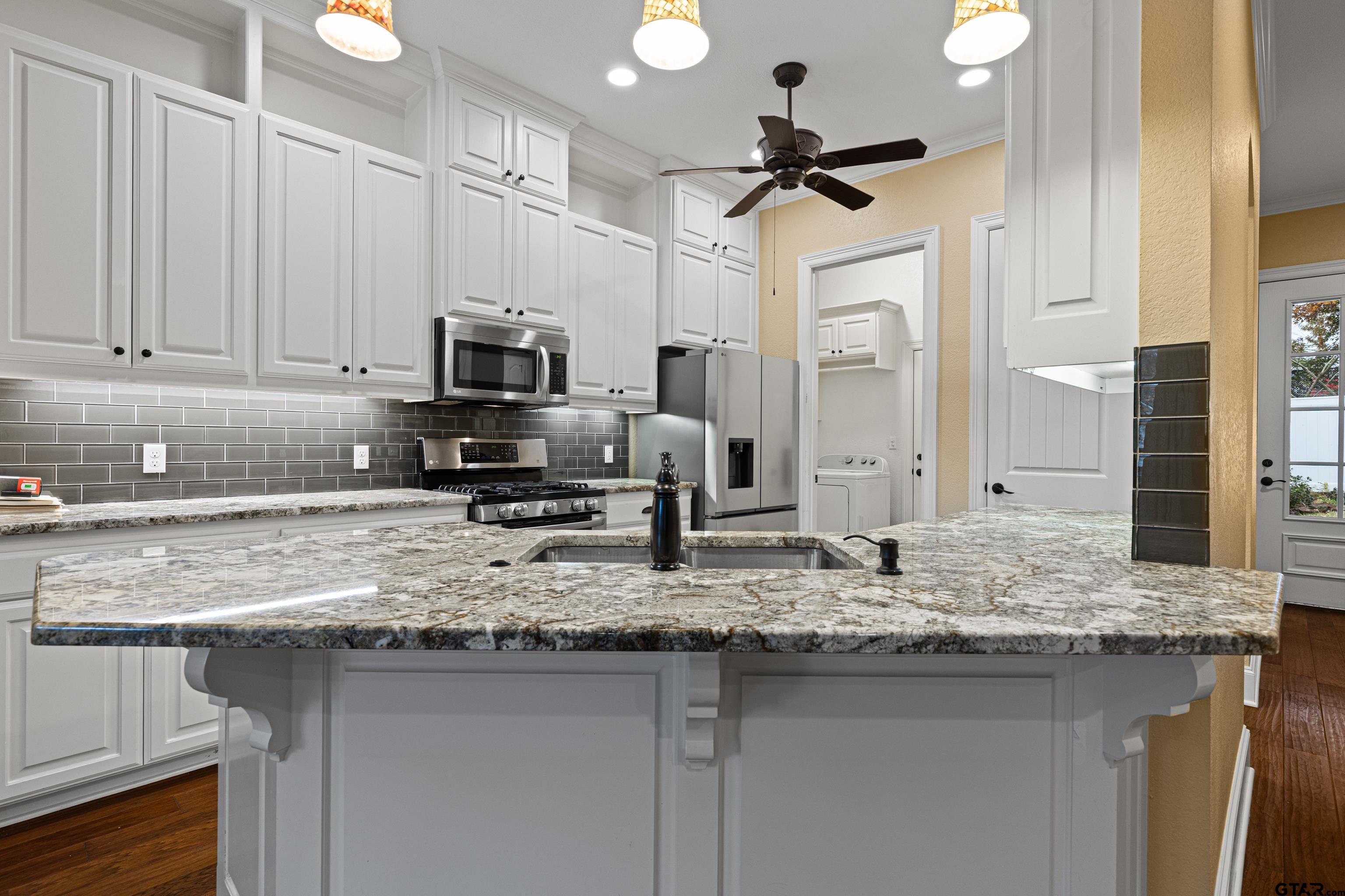 3949 Hanover Place Tyler, TX 75701 - Photo 13 of 43 a kitchen with granite countertop a sink stainless steel appliances white cabinets and a granite counter tops