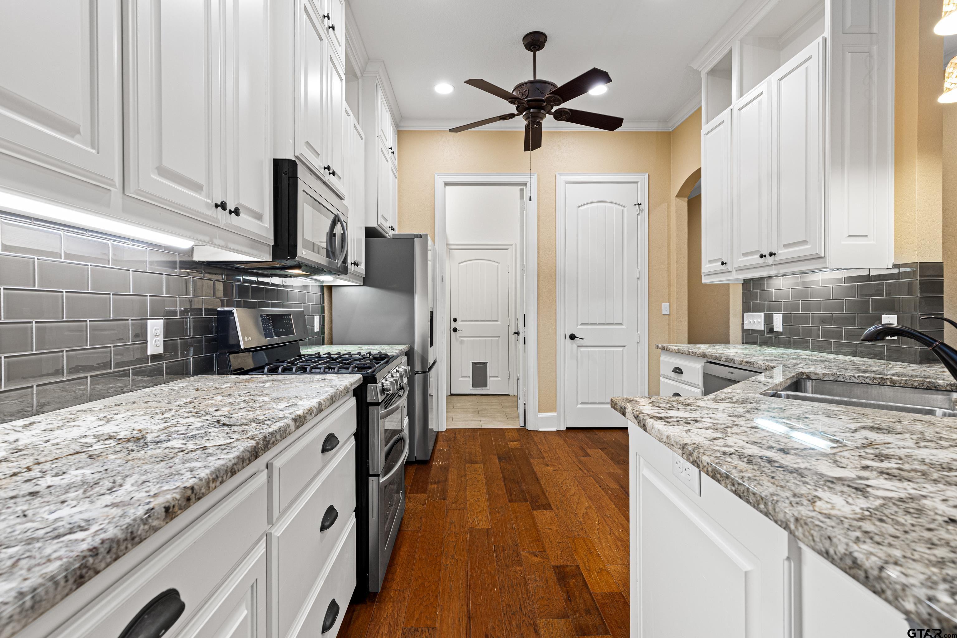 3949 Hanover Place Tyler, TX 75701 - Photo 14 of 43 a large kitchen with kitchen island a large counter top space a sink stainless steel appliances and cabinets