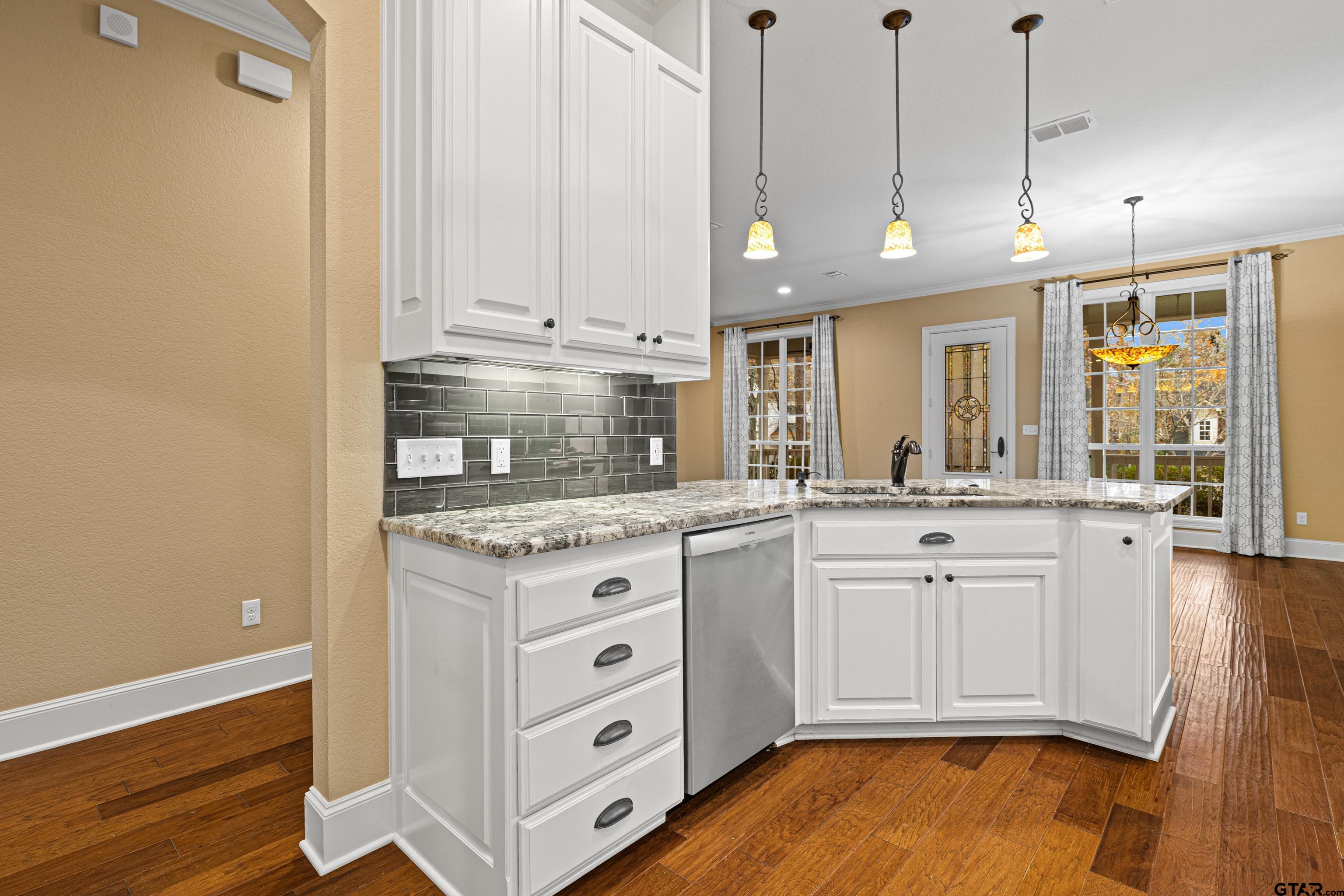 3949 Hanover Place Tyler, TX 75701 - Photo 18 of 43 a kitchen with granite countertop a stove a sink and white cabinets with wooden floor