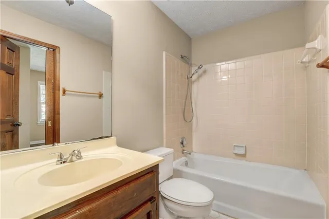a bathroom with a granite countertop bathtub shower sink vanity mirror and toilet