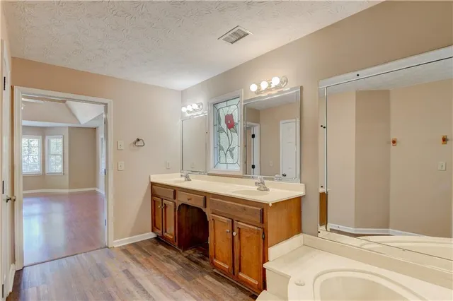 a spacious bathroom with a double vanity sink a large mirror and a shower