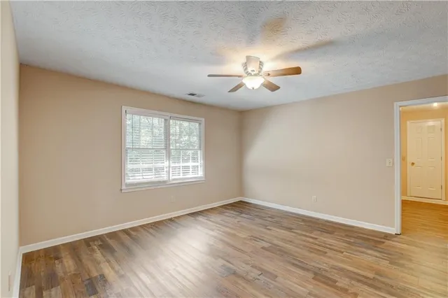 a view of an empty room with a window and wooden floor