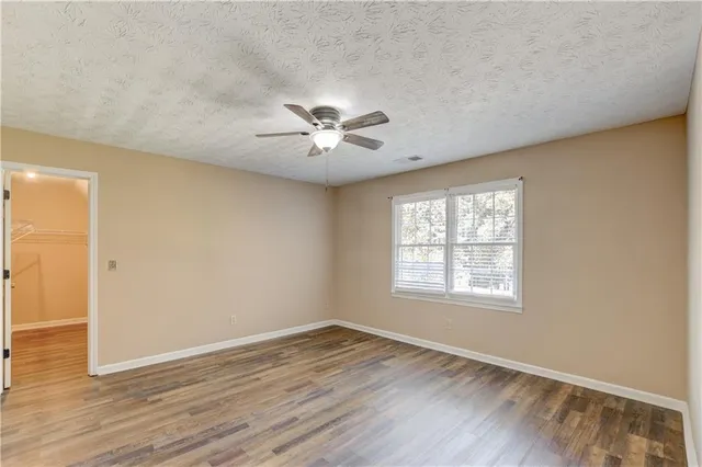 a view of an empty room with a window and wooden floor