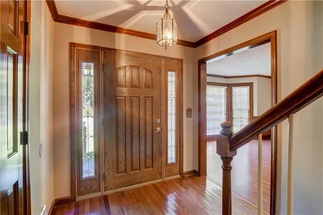 a view of front door with hallway and wooden floor