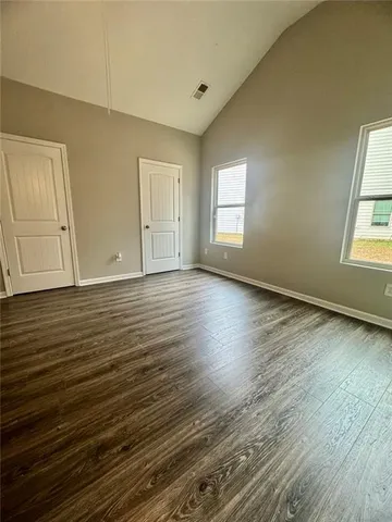 an empty room with wooden floor and fan