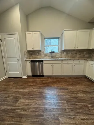 an empty room with wooden floor a fireplace and windows