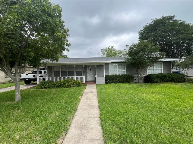a front view of a house with a yard and trees