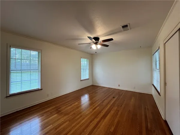 a view of an empty room with wooden floor and a window