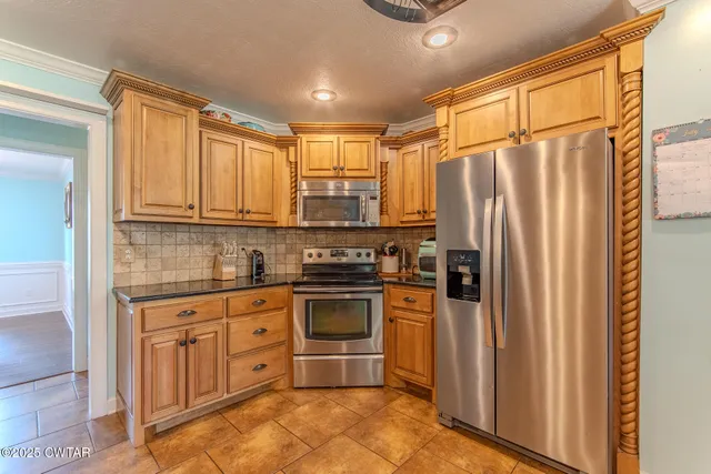 a kitchen with stainless steel appliances granite countertop a refrigerator a sink and white cabinets