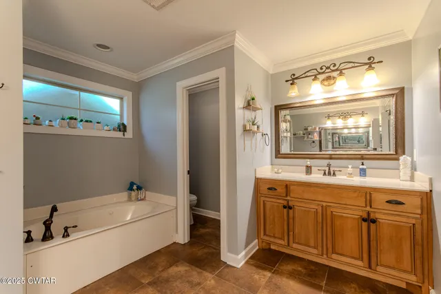 a spacious bathroom with a tub sink and mirror