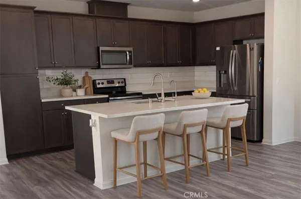 a kitchen with stainless steel appliances a stove a sink refrigerator and a microwave with wooden floor