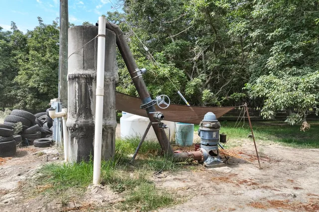 a view of a wooden house with a bench and next to a yard