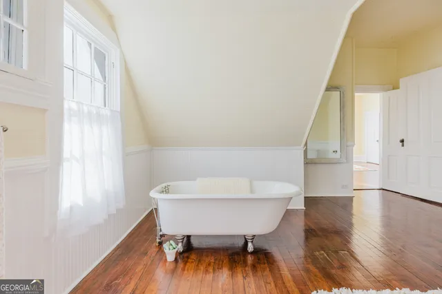 a view of an empty room with window and wooden floor