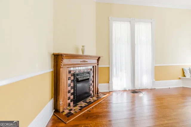 a view of an empty room with wooden floor and a fireplace