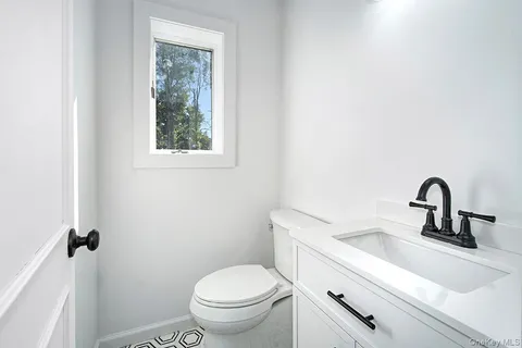 a bathroom with a sink mirror toilet and window