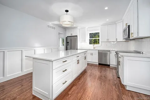 a kitchen with white cabinets appliances and wooden floor