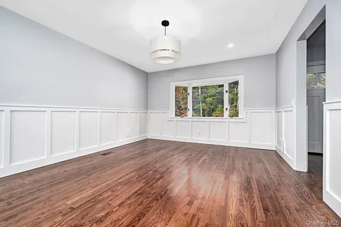an empty room with wooden floor chandelier fan and windows
