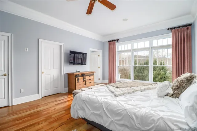 a bedroom with a bed a flat screen tv and a large window