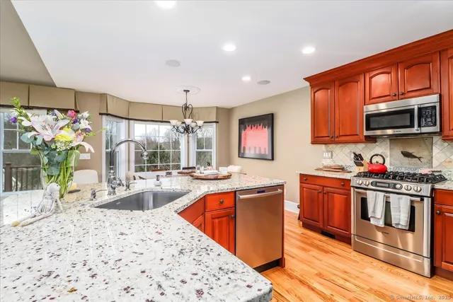 a kitchen with stainless steel appliances kitchen island granite countertop a sink stove and refrigerator