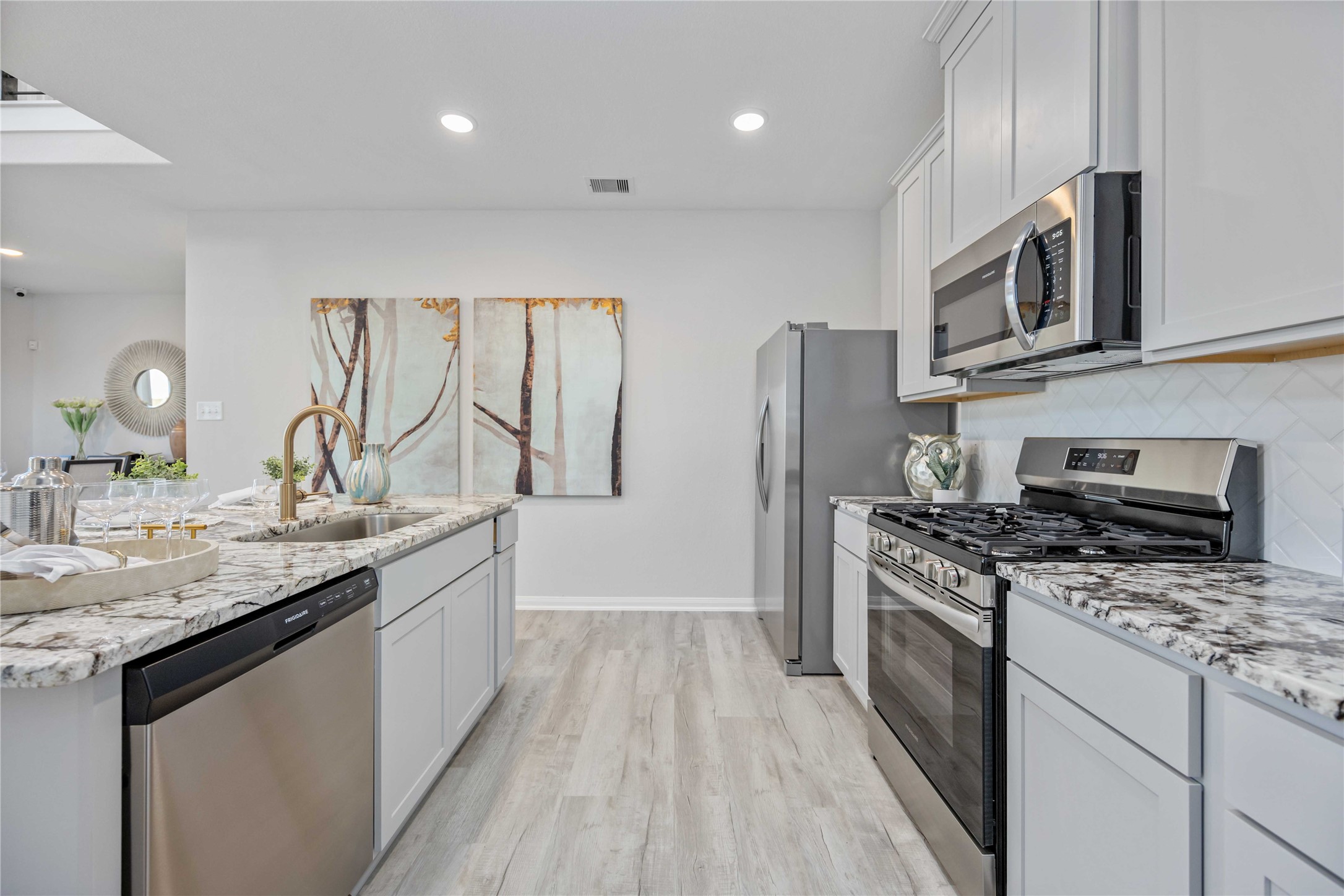 22470 Kinley Street New Caney, TX 77357 - Photo 2 of 21 a kitchen with stainless steel appliances granite countertop a stove top oven a sink dishwasher a refrigerator and a microwave oven with wooden floor