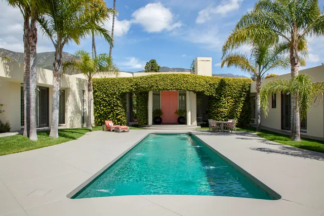 front view of a house with a yard and palm trees