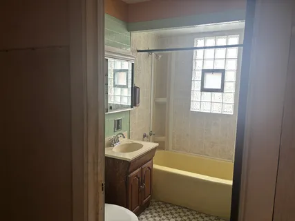a bathroom with a sink a bathtub and next to a window