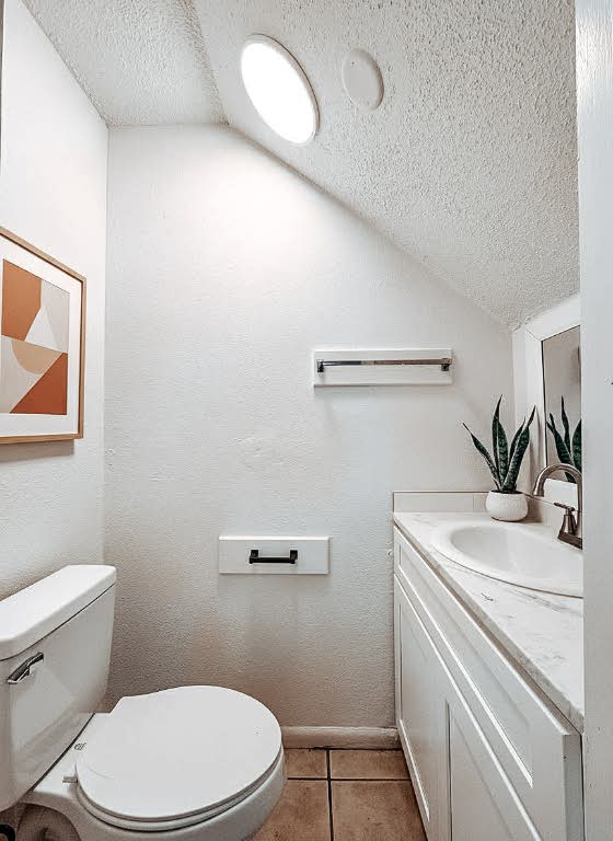 5810 Sweeney Circle, Unit D Austin, TX 78723 - Photo 12 of 18 Bathroom featuring vaulted ceiling, a textured ceiling, light tile patterned floors, and vanity