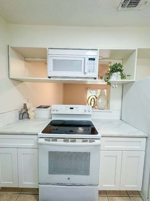 5810 Sweeney Circle, Unit D Austin, TX 78723 - Photo 7 of 18 Kitchen with open shelves, white appliances, white cabinetry, light tile patterned flooring, and a textured ceiling