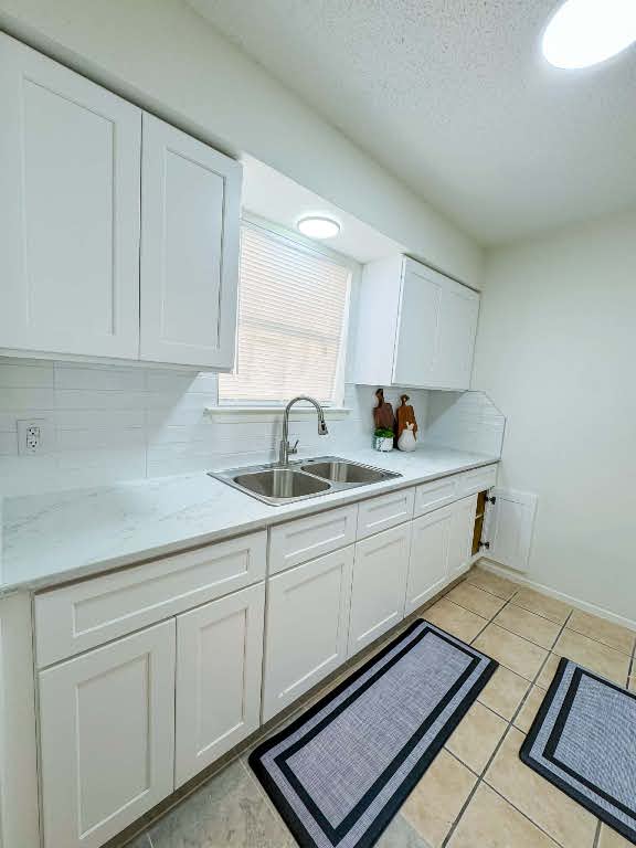 5810 Sweeney Circle, Unit D Austin, TX 78723 - Photo 8 of 18 Kitchen featuring white cabinetry, decorative backsplash, a textured ceiling, light tile patterned floors, and light stone counters