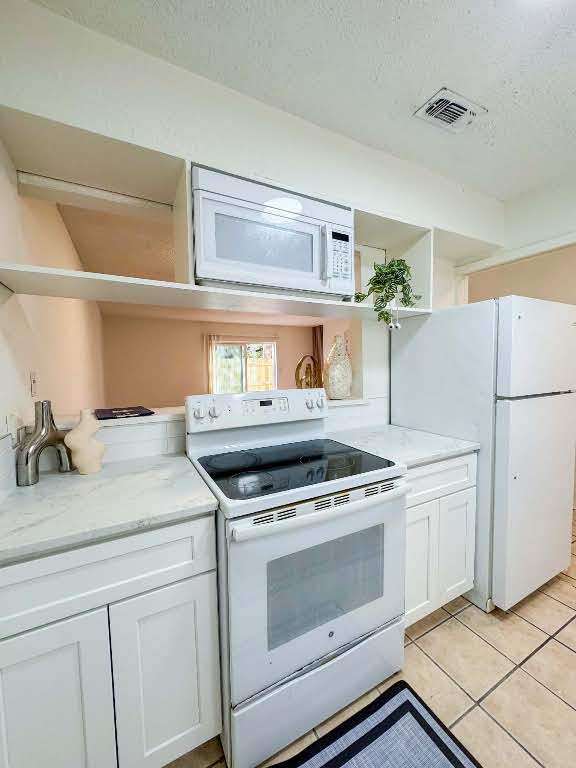 5810 Sweeney Circle, Unit D Austin, TX 78723 - Photo 9 of 18 Kitchen featuring white cabinets, white appliances, open shelves, light stone counters, and a textured ceiling