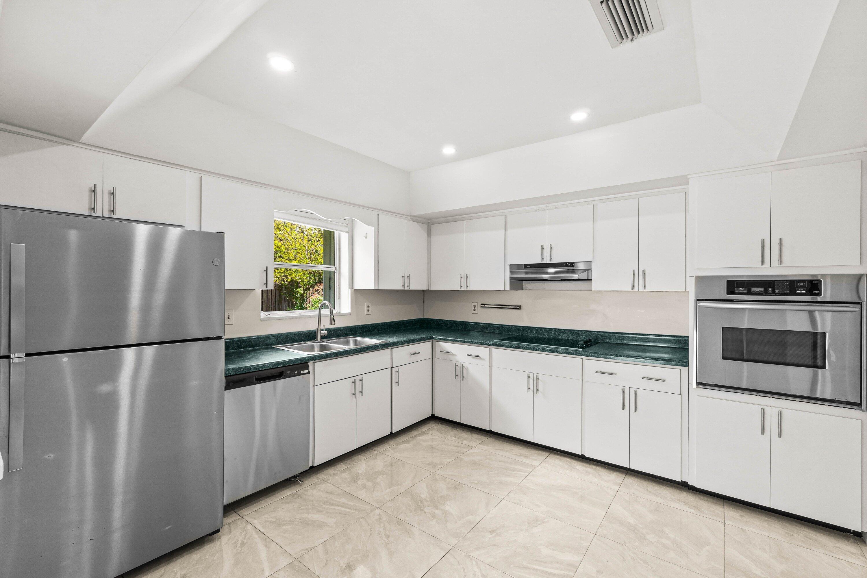 1290 Southwest 8th Street Boca Raton, FL 33486 - Photo 4 of 29 a kitchen with granite countertop a refrigerator sink and white cabinets