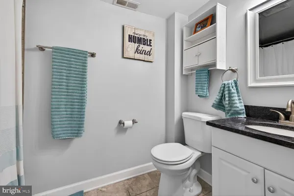 a bathroom with a granite countertop toilet sink and mirror