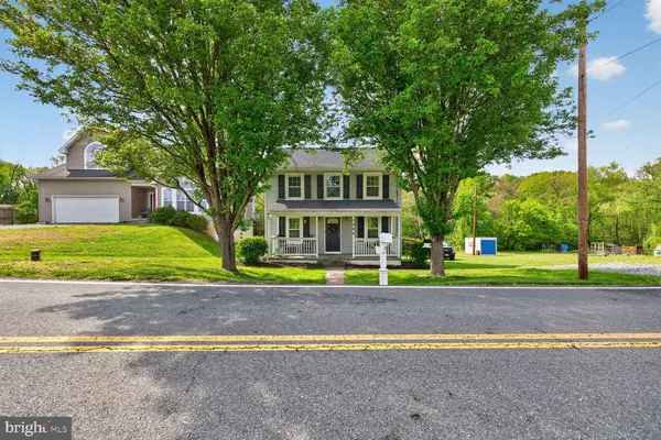 a view of a house with a yard and large trees