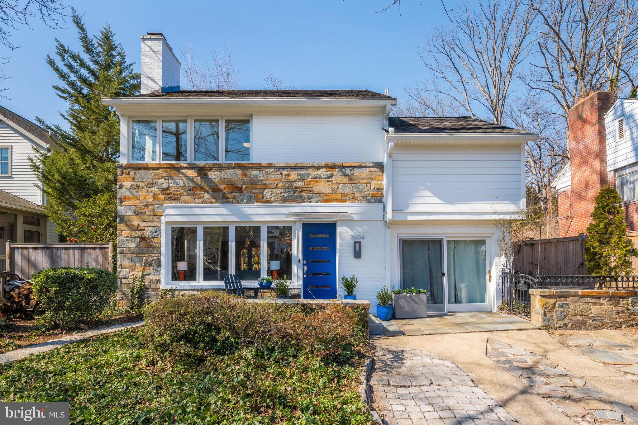 a view of a white house with large windows and a small yard