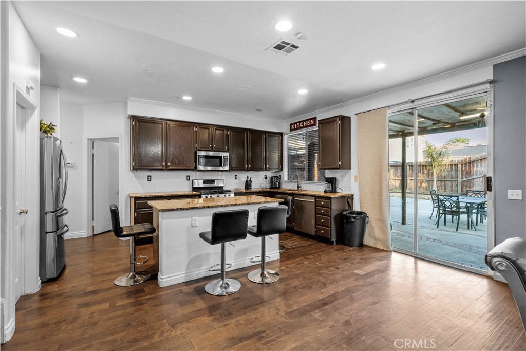 3807 Seattle Street Hemet, CA 92545 - Photo 9 of 38 a kitchen with a refrigerator a stove top oven a sink dishwasher a dining table and chairs with wooden floor