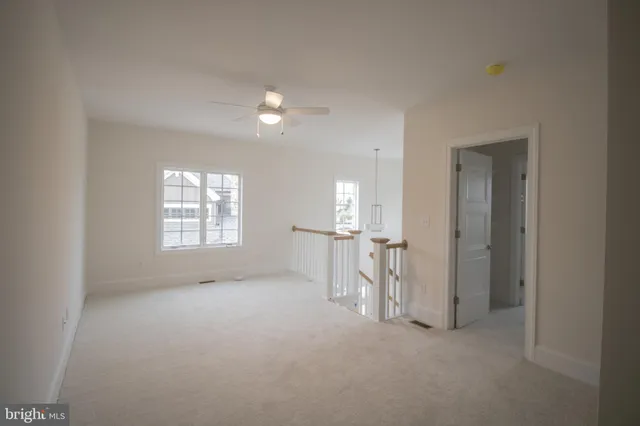 an empty room with chandelier fan and windows