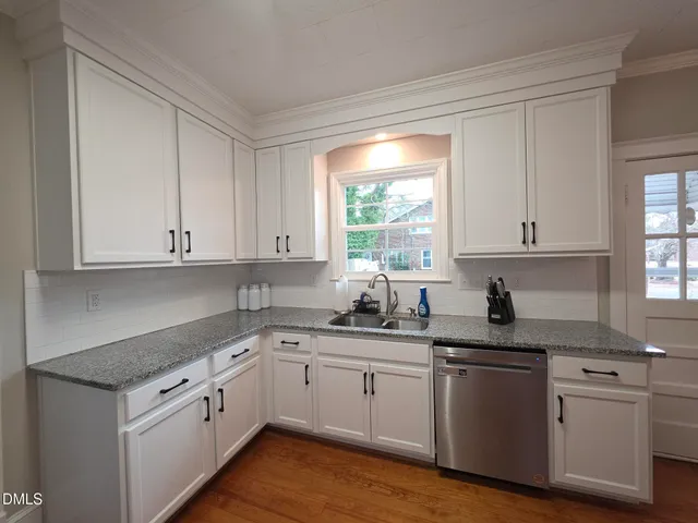 a kitchen with granite countertop white cabinets white appliances a sink and a window