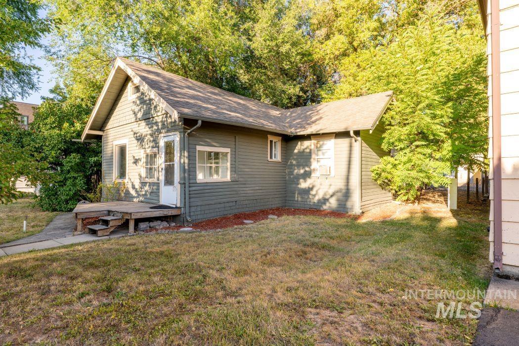 View of side of property featuring a lawn, a deck, and roof with shingles