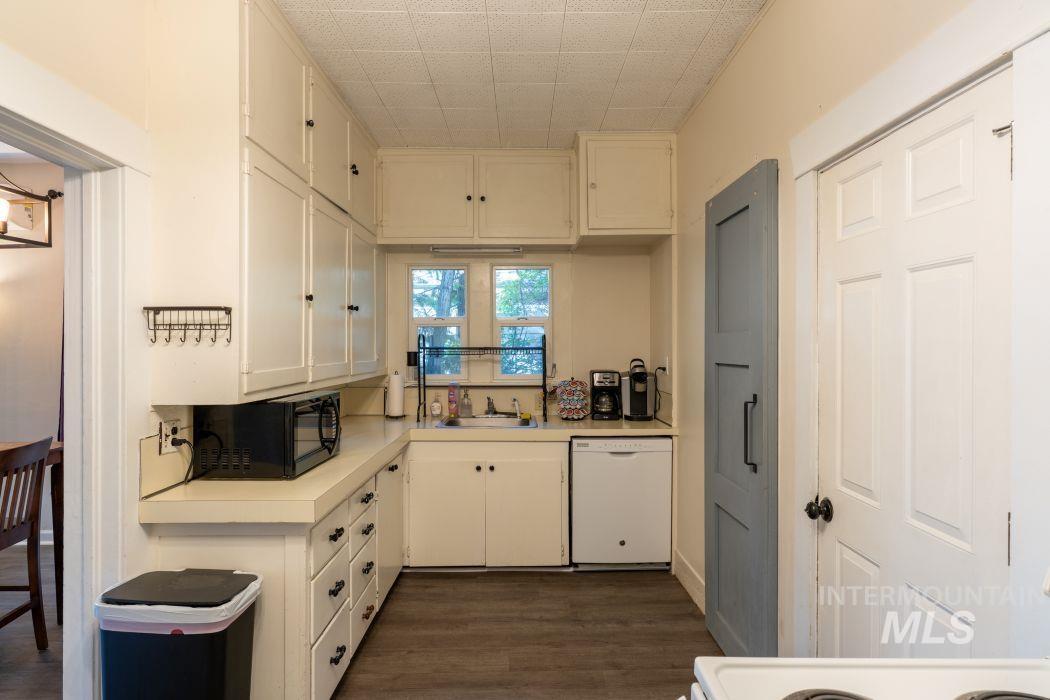 112 South Asbury Street Moscow, ID 83843 - Photo 12 of 26 Kitchen with light countertops, white dishwasher, white cabinetry, dark wood finished floors, and black microwave
